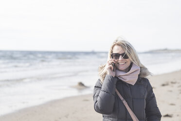 Porträt einer glücklichen Frau beim Telefonieren am Strand - CHPF00391