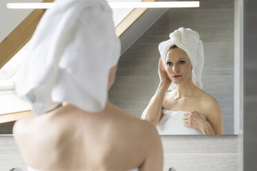 Frau betrachtet ihr Spiegelbild im Badezimmer - CHPF00394