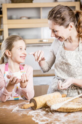Mother and daughter baking bread in kitchen together - WESTF22993