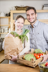 Smiling couple with box of vegetables in kitchen - WESTF23006