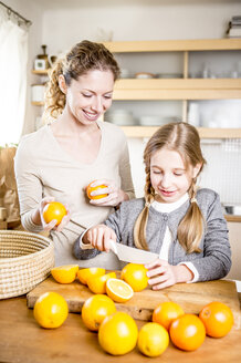 Mutter und Tochter schneiden Orangen in der Küche - WESTF23009