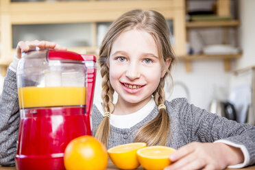 Porträt eines lächelnden Mädchens, das frisch gepressten Orangensaft herstellt - WESTF23011