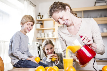 Frau gießt frisch gepressten Orangensaft in ein Glas für Kinder - WESTF23012