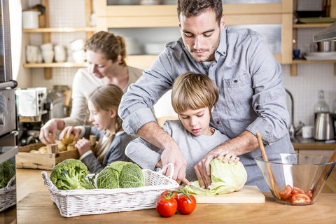 Familie bereitet Salat in der Küche zu, lizenzfreies Stockfoto