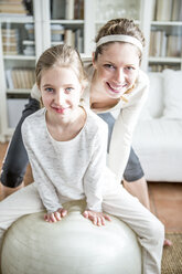 Mother and daughter with fitness ball at home - WESTF23029