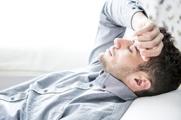 Man lying on couch with closed eyes - WESTF23051