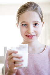 Portrait of smiling girl holding glass of milk - WESTF23054