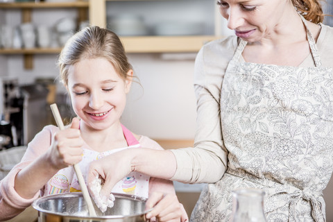 Mother and daughter baking in kitchen together stock photo