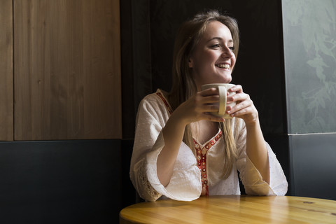 Porträt einer lächelnden Frau mit einer Tasse Kaffee in einem Kaffeehaus, lizenzfreies Stockfoto