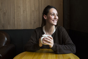 Portrait of smiling woman with cup of coffee in a coffee shop - ABZF01969