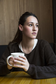 Porträt einer ernsten Frau mit einer Tasse Kaffee in einem Kaffeehaus - ABZF01970