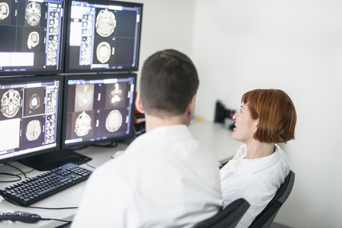 Two doctors discussing x-ray images on computer screen stock photo