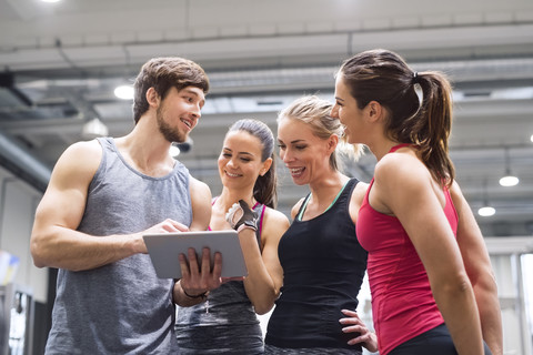 Gruppe glücklicher Sportler mit Tablet nach dem Training im Fitnessstudio, lizenzfreies Stockfoto