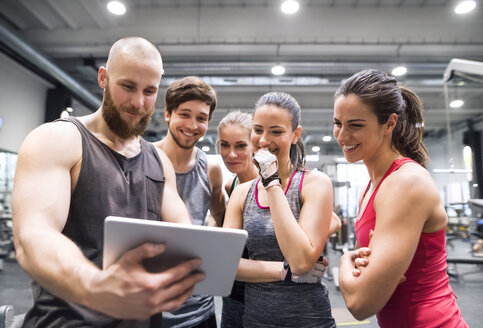 Gruppe glücklicher Sportler mit Tablet nach dem Training im Fitnessstudio - HAPF01618