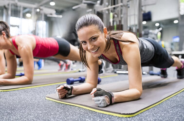 Porträt einer lächelnden jungen Frau, die im Fitnessstudio trainiert - HAPF01623