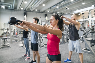 Gruppe von Sportlern beim Training mit Kettlebells in einer Turnhalle - HAPF01627