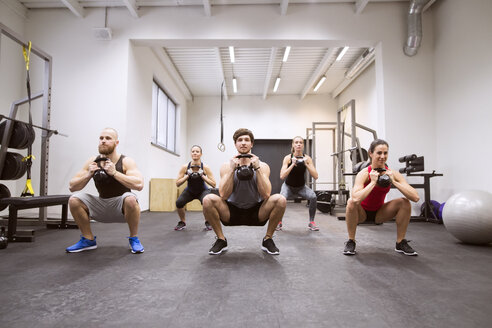 Gruppe von Sportlern beim Training mit Kettlebells in einer Turnhalle - HAPF01631