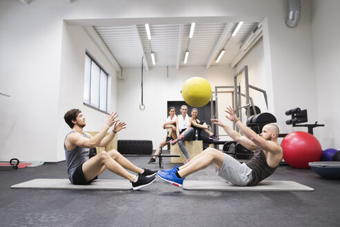 Zwei Sportler trainieren mit einem Ball in einer Turnhalle, während ihre Trainingspartner zusehen - HAPF01635