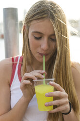 Junge Frau trinkt gelbes Getränk - KKAF00726