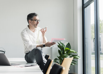 Businessman using cell phone in a conference room - UUF10497