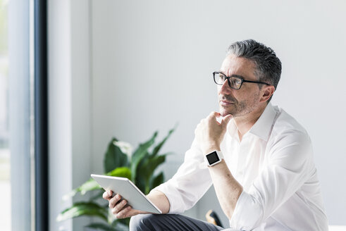 Portrait of pensive businessman with tablet and smartwatch - UUF10498