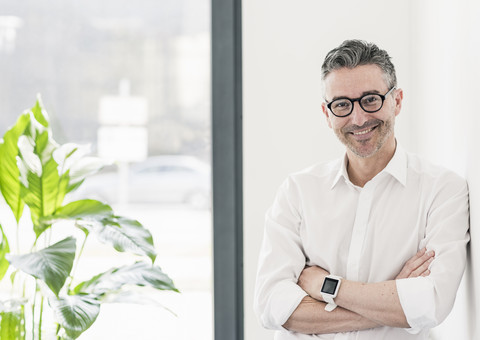 Porträt eines lächelnden Geschäftsmannes mit Smartwatch und Brille, lizenzfreies Stockfoto