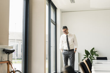 Laughing businessman standing in conference room - UUF10507