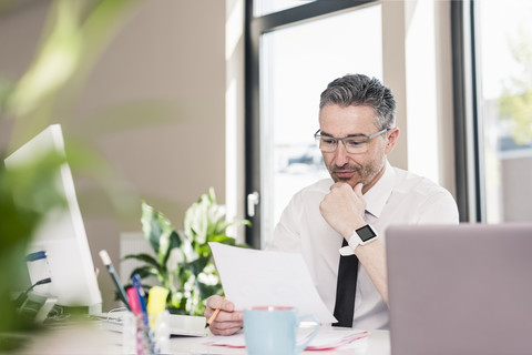 Geschäftsmann arbeitet am Schreibtisch in seinem Büro, lizenzfreies Stockfoto