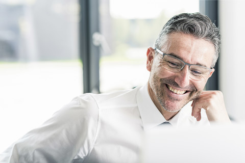 Porträt eines lächelnden Geschäftsmannes mit Bartstoppeln und Brille, lizenzfreies Stockfoto