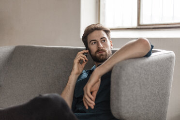 Portrait of young man on the phone sitting on couch - JOSF00730