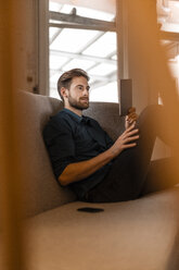 Porträt eines jungen Freiberuflers mit Tablet auf der Couch - JOSF00732