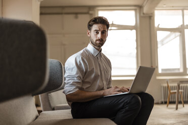 Portrait of young businessman using laptop in a loft - JOSF00734