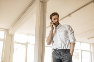 Portrait of young businessman on the phone in a loft - JOSF00737