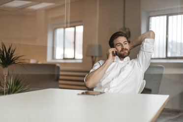 Porträt eines jungen Freiberuflers am Telefon in einem Loft - JOSF00744