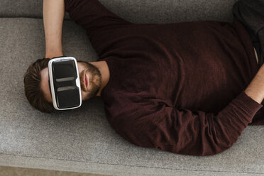 Man lying on the couch using Virtual Reality Glasses - JOSF00754