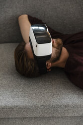 Man lying on the couch using Virtual Reality Glasses - JOSF00755