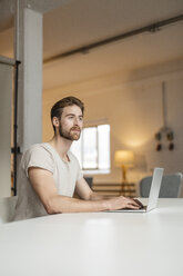 Portrait of young man working on laptop in a loft - JOSF00757