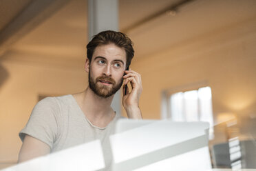 Porträt eines jungen Mannes beim Telefonieren in einem Loft - JOSF00760