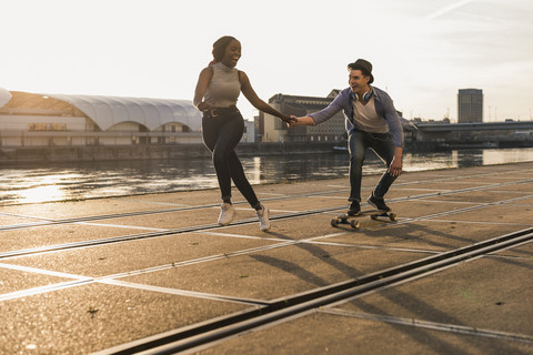 Junges Paar beim Skateboarden am Flussufer, lizenzfreies Stockfoto