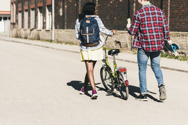 Young couple with bicycle and skateboard walking in the street - UUF10552