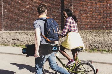 Junges Paar mit Fahrrad und Skateboard zu Fuß auf der Straße - UUF10553