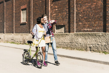 Junges Paar mit Fahrrad und Skateboard macht Smartphone-Selfies - UUF10554