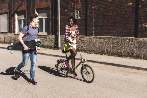 Young couple with bicycle and skateboard walking in the street - UUF10559