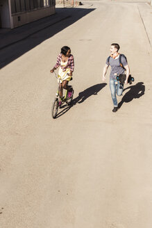 Glückliches Paar beim Laufen und Radfahren auf der Straße - UUF10560