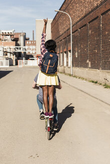 Young couple riding bicycle with girl standing on rack - UUF10564