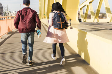 Junges Paar mit Skateboard auf einer Brücke - UUF10575