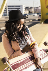 Young woman sitting on bridge using smartphone - UUF10582