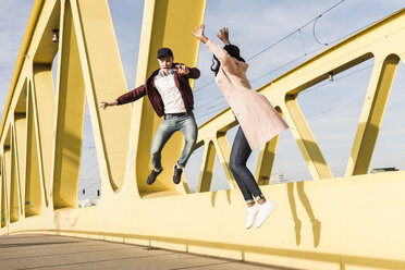 Happy couple jumping on bridge - UUF10588