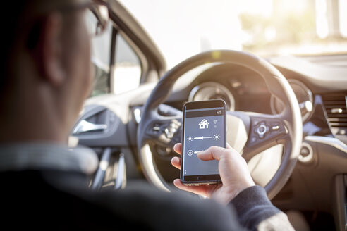 Man in car adjusting devices at home via smartphone - NAF00083