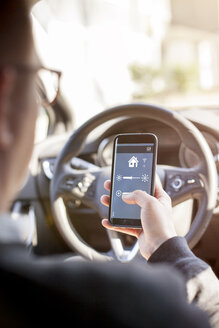 Man in car adjusting devices at home via smartphone - NAF00084